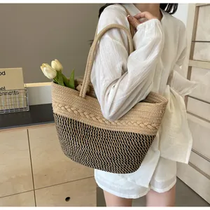 Détail d'un sac cabas bicolore en paille tissée porté par une femme mannequin