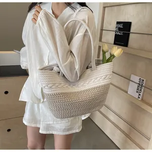 Vue rapprochée d'un sac cabas en paille tissée à la main porté par un mannequin.