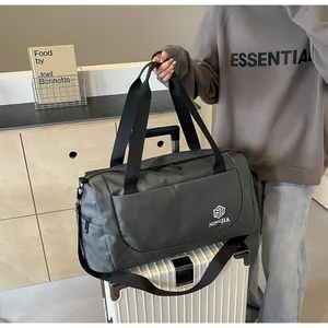 Close-up of a large grey travel duffel bag held by model resting on a white suitcase