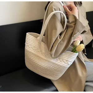Vue détaillée d'un sac cabas en paille tressée avec motif pied-de-poule pour la plage.