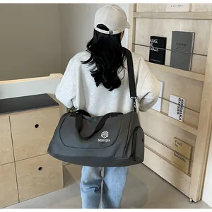 Large grey travel duffel bag for women shown in a modern lifestyle indoor setting.