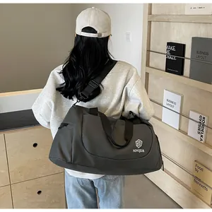 Model carrying large dark grey duffle bag over her shoulder in a stylish indoor setting