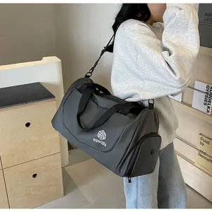 Close-up of a large grey travel bag worn by a model in a modern interior