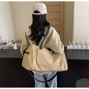 Large beige duffel bag for travel or business carried by a woman seen from behind
