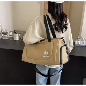 Large capacity khaki travel bag carried by a person in a minimalist cafe setting.