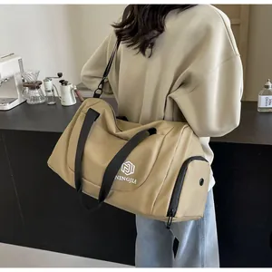 Large capacity tan travel duffel bag carried by a model in a modern lifestyle setting