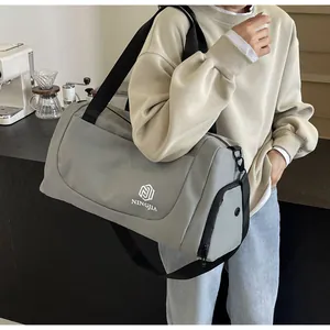 Detail view of a large capacity grey travel duffel bag held by a model in lifestyle setting