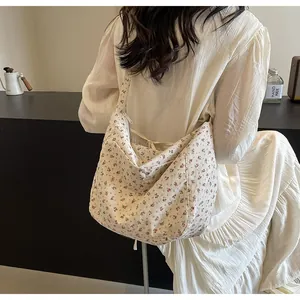 Primer plano de un bolso tote con estampado floral llevado con vestido blanco