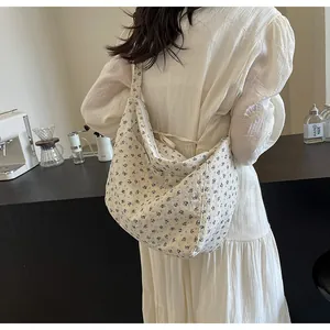 Vista detallada del bolso hobo de lona floral llevado por modelo en ambiente de café
