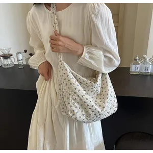 Vista detallada del bolso tote de lona con flores con un vestido blanco elegante.