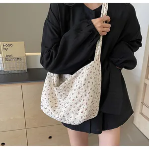 Detalle de un pequeño bolso tote de lona con flores llevado por una modelo