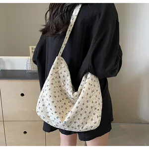Detalle de un bolso tote de lona con pequeñas flores azules sobre fondo crema