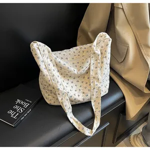 Vista detallada de un bolso tote de flores blancas con estampados azules en un banco