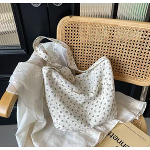 Vista detallada de un bolso de lona con estampado floral blanco en una silla de mimbre.