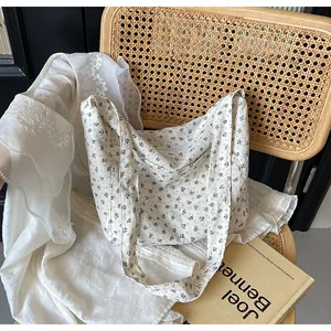 Detalle de un bolso tote de lona floral con motivos azules en una silla elegante.