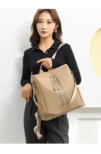 Donna asiatica con un grande zaino beige da pendolare con eleganti dettagli borchiati