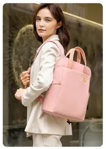 Detailed view of a stylish pink square backpack worn by a model in a modern indoor setting.