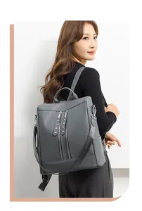 Dettaglio di uno zaino grigio versatile indossato da una modella, con eleganti zip decorative.