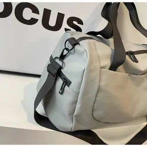 Close-up of a light grey travel bag highlighting the strap and side zipper pocket.