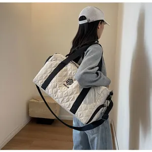 Stylish white quilted duffel bag featuring black straps for travel, gym, and weekend getaways