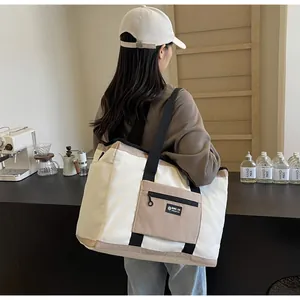 Vista posteriore di una modella con una grande borsa da viaggio in tela bicolore in un caffè
