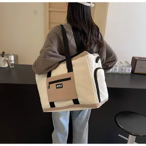 Grande borsa da viaggio in tela crema con dettagli kaki portata a spalla da una modella.