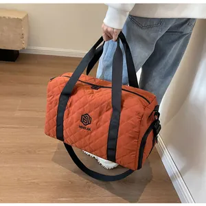 Stylish orange quilted duffel bag for travel and gym being held by person indoors