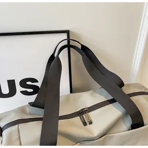 Detail of waterproof zipper and durable straps on a light grey travel duffle bag.