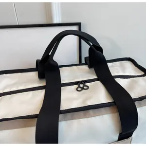 Dettaglio delle robuste doppie cerniere e dei manici neri sulla borsa da viaggio crema