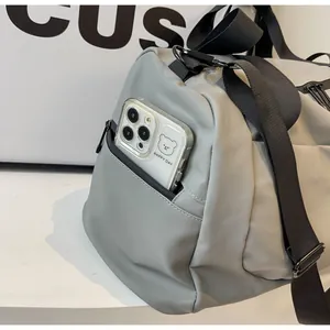 Detail of side pocket on grey large capacity travel duffel bag for phone storage.