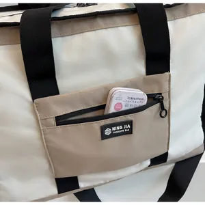 Dettaglio della tasca anteriore con zip su borsa da viaggio bianca capiente