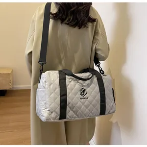 Gray quilted travel duffel bag carried by person in minimalist lifestyle setting
