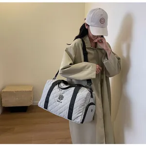 Model carrying a stylish quilted travel duffel bag in a modern indoor setting