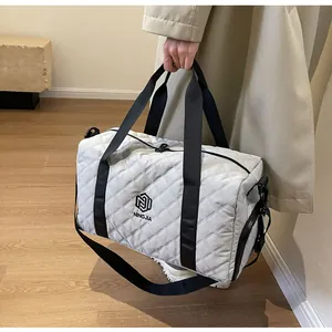 Large diamond-quilted travel duffel bag with black straps in a modern lifestyle setting.