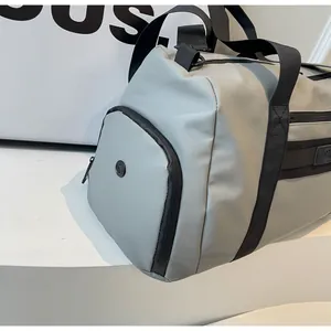 Detail of grey travel duffel bag showing side pocket with air vent and black straps.