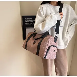 Quilted pink travel duffel bag on model's shoulder, perfect for gym or short getaway