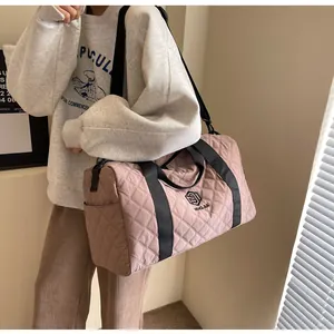 Close-up detail of a stylish pink quilted travel duffle bag with black straps and logo