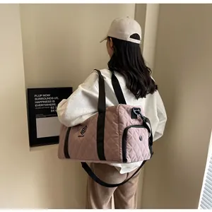 Premium pink quilted travel duffel bag carried by a model in a minimalist room