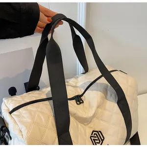 Close-up of black reinforced handles on a chic white quilted travel duffle bag.