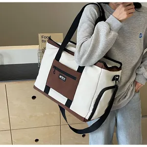 Borsa da viaggio in tela capiente con dettagli marroni sulla spalla di una modella