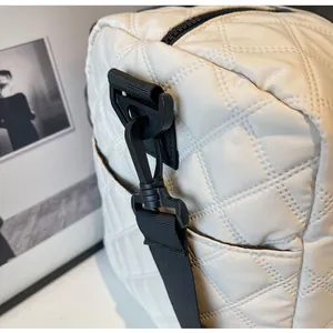Close-up detail of white quilted gym bag with durable black strap and metal hook.