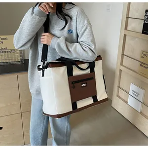 Borsa da viaggio capiente bicolore in tela indossata da una modella in un ambiente stile casual