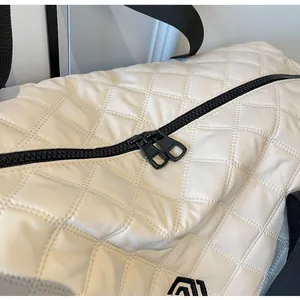 Close-up view of a stylish cream white quilted travel bag showing premium black zipper details