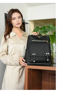 Zaino moderno in pelle nera da viaggio indossato da una modella in un ambiente elegante.