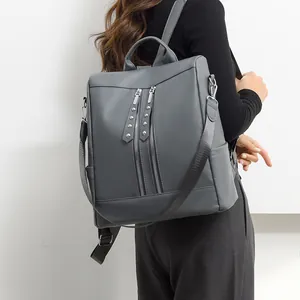 Zaino moderno in pelle grigia da donna, ideale per il lavoro e lo stile quotidiano.