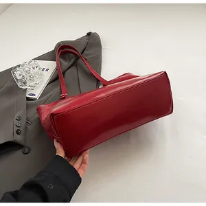 Detailed view of large red tote bag showing smooth texture and bottom structure.