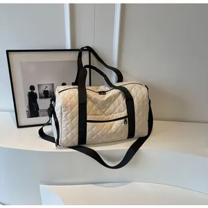 Elegant quilted cream travel duffle bag displayed on a white minimalist interior surface