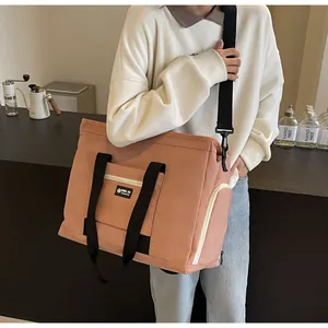 Dettaglio di una grande borsa da viaggio rosa con tracolla nera indossata da modella