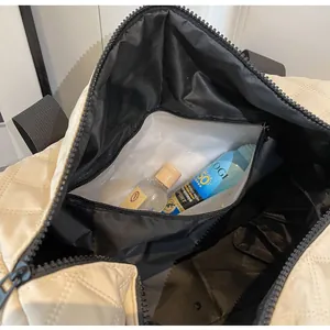 Detail view of the waterproof wet/dry separation pocket in a beige quilted travel bag.