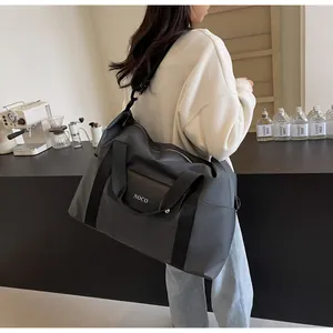 Grote zwarte reistas gedragen door een model in een minimalistische setting
